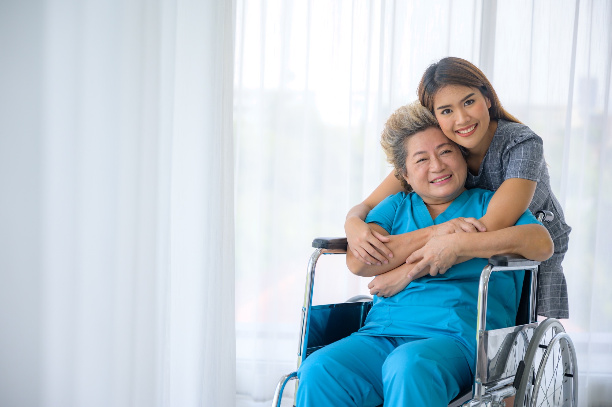 Asian daughter or care assistant helping support senior woman or mother